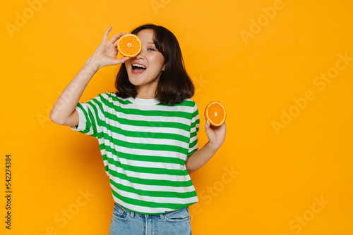 Asian young woman wearing stripped t-shirt smiling while holding orange