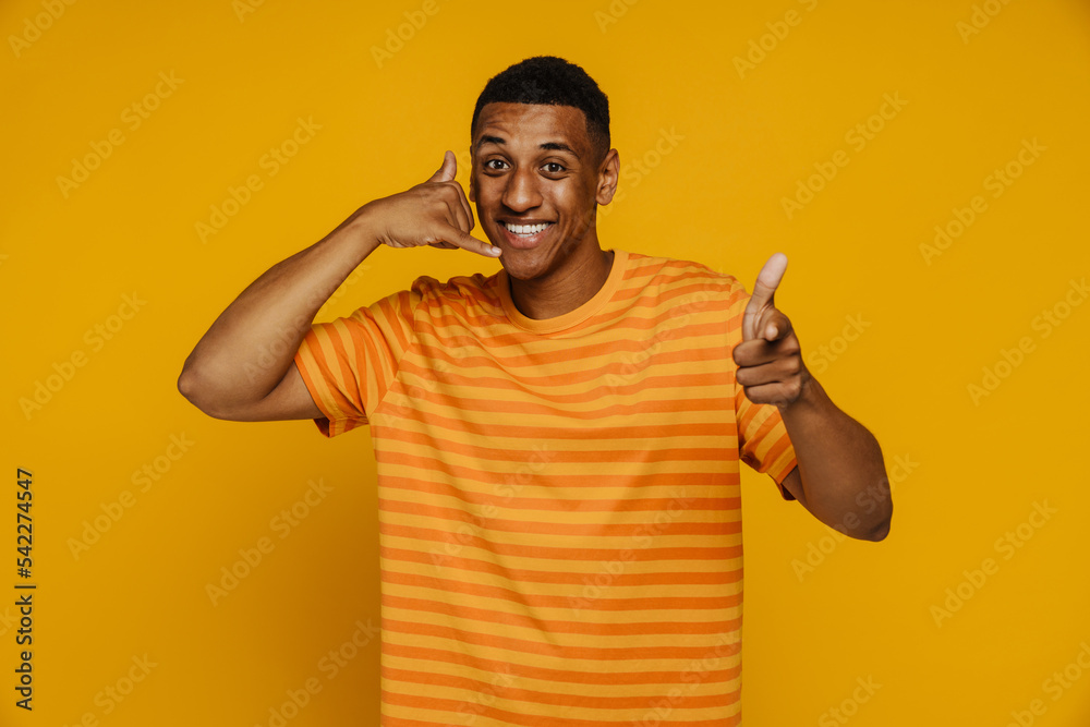 Afro man smiling and doing call gesture while pointing at camera Afro man smiling and doing call gesture while pointing at camera