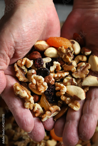 A handful of nuts and dried fruits in male palms. Healthy sweets or snack.