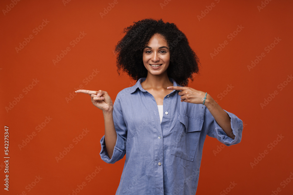 Young beautiful smiling curly woman pointing aside both hands fingers Young beautiful smiling curly woman pointing aside both hands fingers