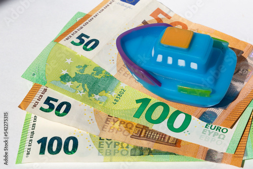 Boat toy standing on euro money. Concept of saving and spending money for a vacation cruise. Expensive budget for rest and last minute sale deals  photo