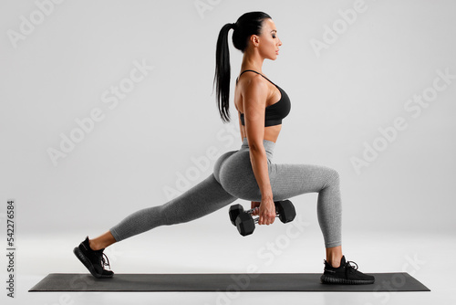 Fitness woman doing lunges exercises for leg muscle workout training. Active girl doing front forward one leg step lunge exercise