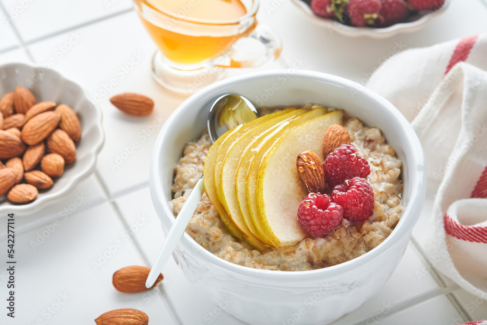 Oatmeal. Bowl of oatmeal porridge with raspberry, pear and honey on gray concrete old table background. Hot and healthy food for Breakfast, top view, flat lay Oatmeal. Bowl of oatmeal porridge with raspberry, pear and honey on gray concrete old table background. Hot and healthy food for Breakfast, top view, flat lay