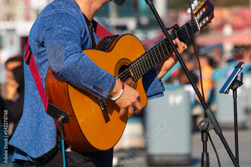 Canvas Print Street performer playing guitar in a square of a city.