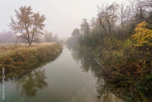 The fog rolls through the countryside over the river during autumn in Ontario, Canada
