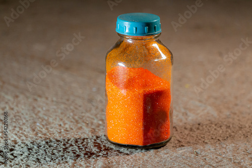 Orange poweder Ammonium dichromate in a glass bottle photo