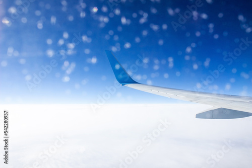 Airplane wing in frozen porthole in a plane during the flight. Amazing scenic view through the aircraft window against the blue sea and sky