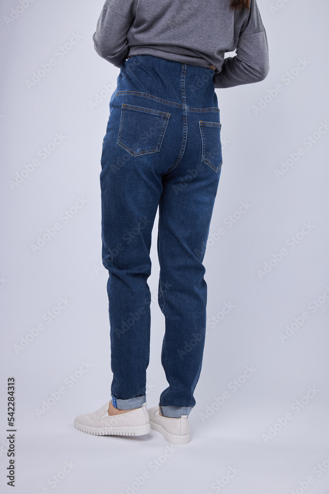 Pregnant woman in blue jeans on a gray background, jeans model for pregnant women Pregnant woman in blue jeans on a gray background, jeans model for pregnant women
