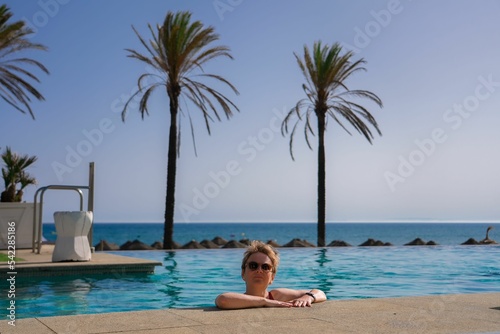 Beautiful shot of a woman posing in the pool with the background of the sea