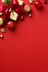 Elegant Christmas vertical banner design. Flat lay Christmas gift box, ornaments, baubles on red background.