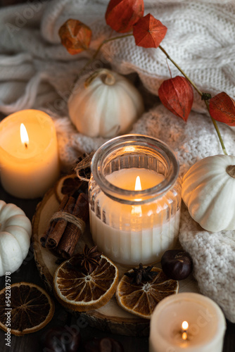 Autumn home composition with aromatic candle, dry citrus, cinnamon, anise. Aromatherapy on a grey fall morning, atmosphere of cosiness and relax. Wooden background close up