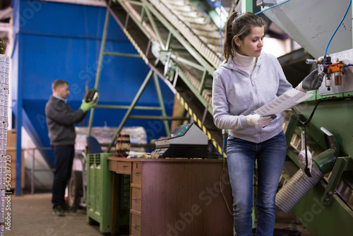Focused woman supervising sensors of machine of olive oil cold pressing on family artisanal factory