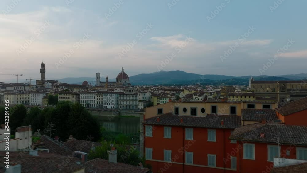 Low flight above old apartment houses along Arno river. Towers and dome in historic city centre in background. Florence, Italy Low flight above old apartment houses along Arno river. Towers and dome in historic city centre in background. Florence, Italy