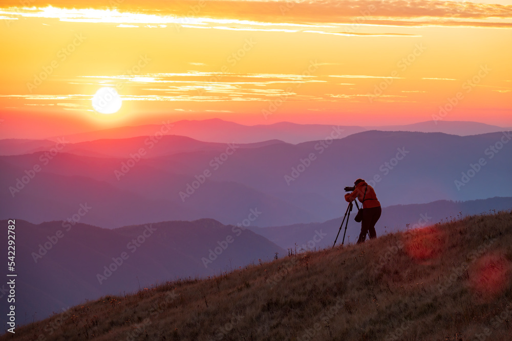 Travel photographer with professional gear makes photos of the sunset