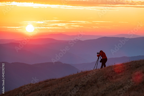 Travel photographer with professional gear makes photos of the sunset