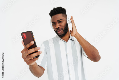 Black bearded man in headphones using mobile phone