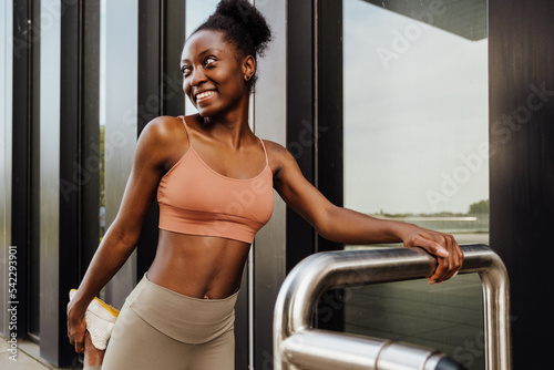 Young beautiful sporty smiling happy african woman stretching her leg