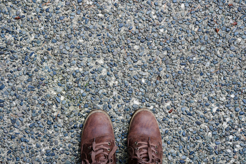 A top view image of a pair of brown hiking boots on a paved stone walkway.