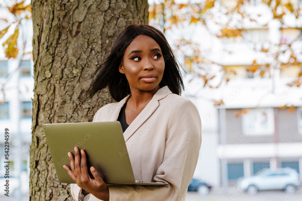 Young black businesswoman using laptop while walking outdoors Young black businesswoman using laptop while walking outdoors