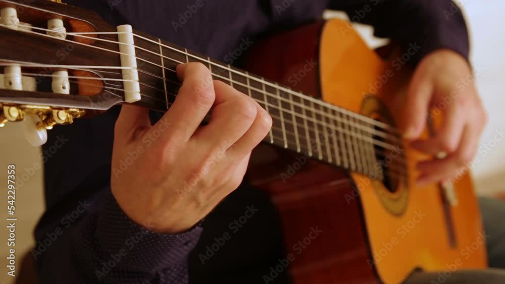 Left-handed male guitarist playing classical nylon-string guitar. Filmed with focus change and studio light. Left-handed male guitarist playing classical nylon-string guitar. Filmed with focus change and studio light.
