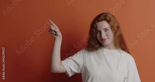 Cheerful woman pointing up at studio. Overjoyed ginger girl points finger