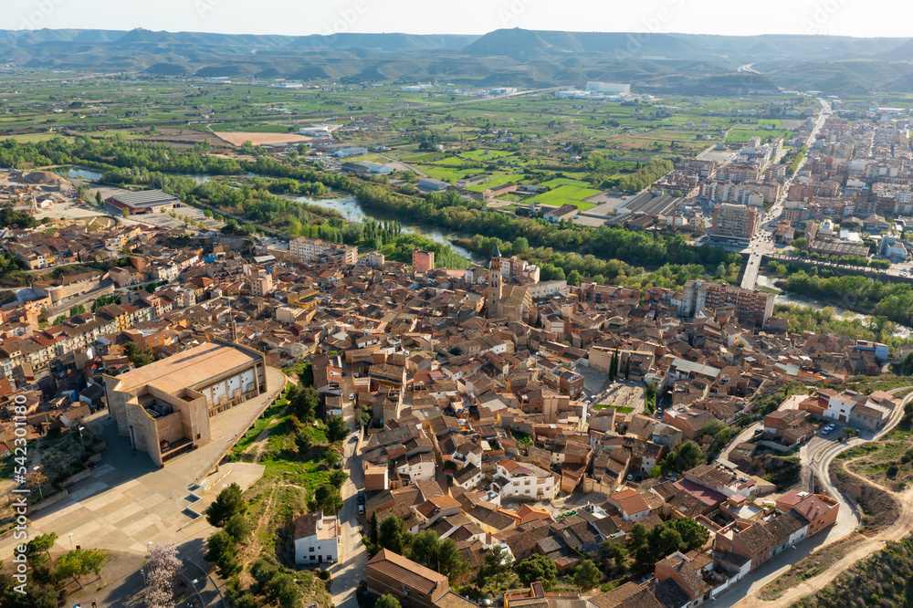 Picturesque spring aerial view of Fraga cityscape overlooking two neighborhoods - historic El casco and contemporary Las Afueras on banks of Cinca river on sunny day, Spain