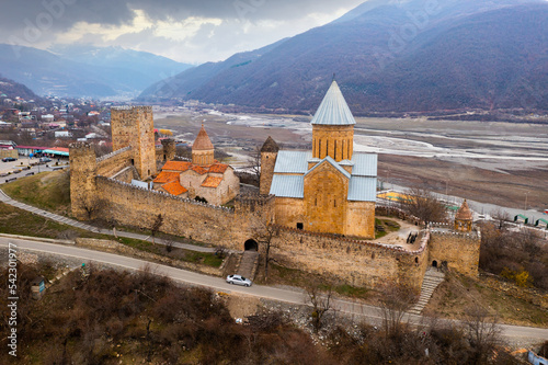 Aerial view of medieval Ananuri fortified ensemble on hill in Aragvi River valley surrounded by Caucasus mountains on spring day, Mtskheta-Mtianeti region, Georgia photo