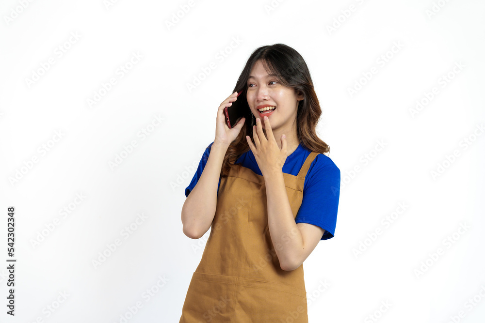 Cheerful young pretty asian woman blue t-shirt and apron coffee owner isolated on white background. call mobile phone, recieve order Cheerful young pretty asian woman blue t-shirt and apron coffee owner isolated on white background. call mobile phone, recieve order