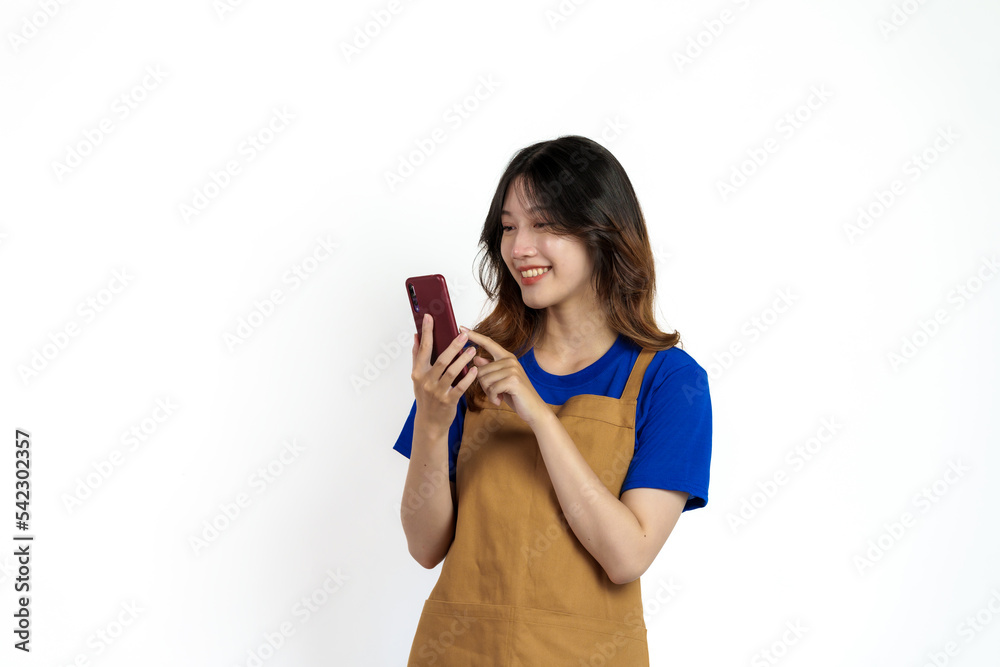 Cheerful young pretty asian woman blue t-shirt and apron coffee owner isolated on white background. Receive orders from the mobile app Cheerful young pretty asian woman blue t-shirt and apron coffee owner isolated on white background. Receive orders from the mobile app