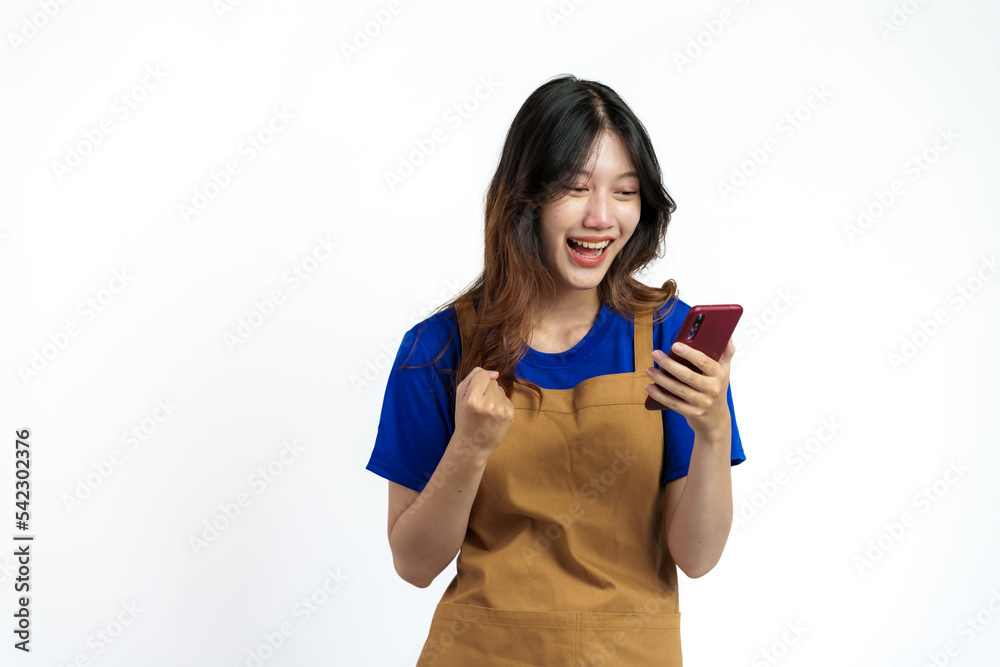 Cheerful young pretty asian woman blue t-shirt and apron coffee owner isolated on white background. Receive orders from the mobile app Cheerful young pretty asian woman blue t-shirt and apron coffee owner isolated on white background. Receive orders from the mobile app