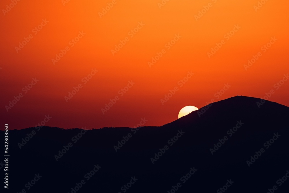 Sun setting behind a silhouette mountain in , Athens, Greece