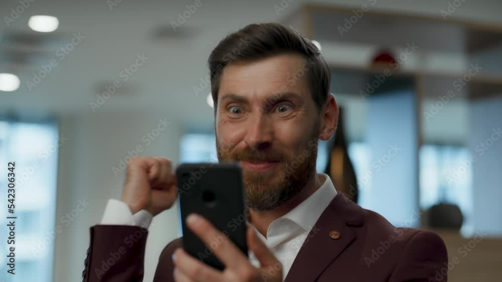 Smiling entrepreneur wondering cellphone at open space. Businessman rejoicing Smiling entrepreneur wondering cellphone at open space. Businessman rejoicing