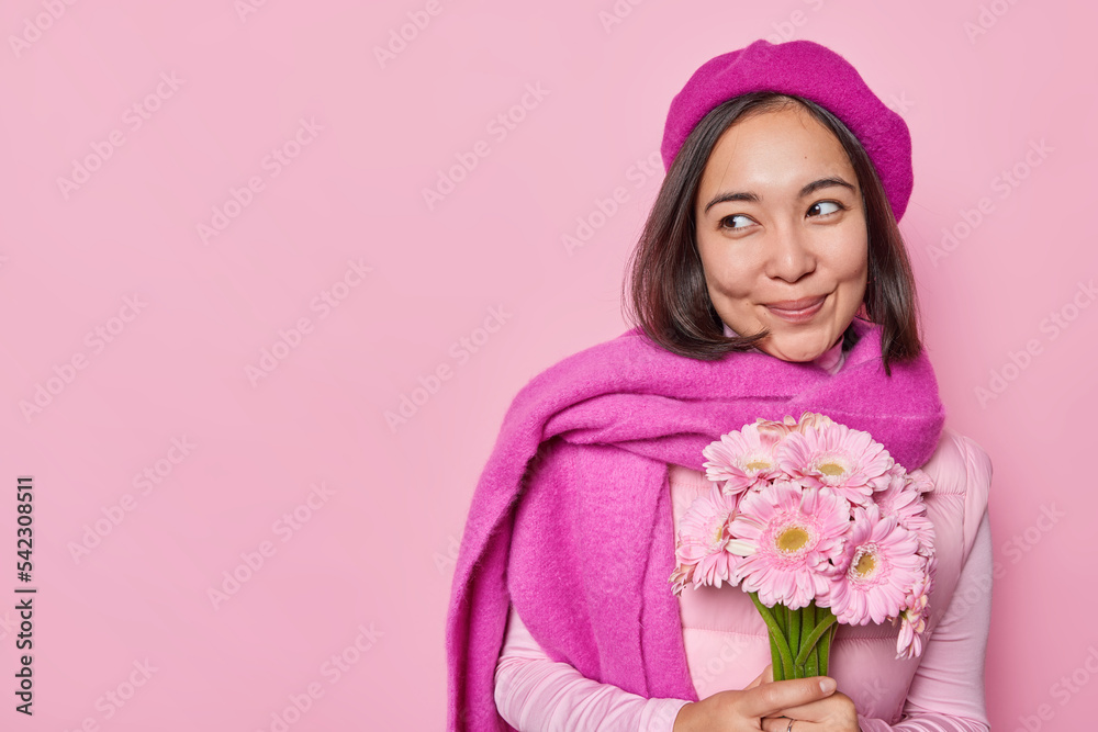 Good looking smiling charming girlfriend holds bouquet of gerberas enjoys her birthday wears beret and scarf around neck isolated over pink background blank space for your advertising content Good looking smiling charming girlfriend holds bouquet of gerberas enjoys her birthday wears beret and scarf around neck isolated over pink background blank space for your advertising content
