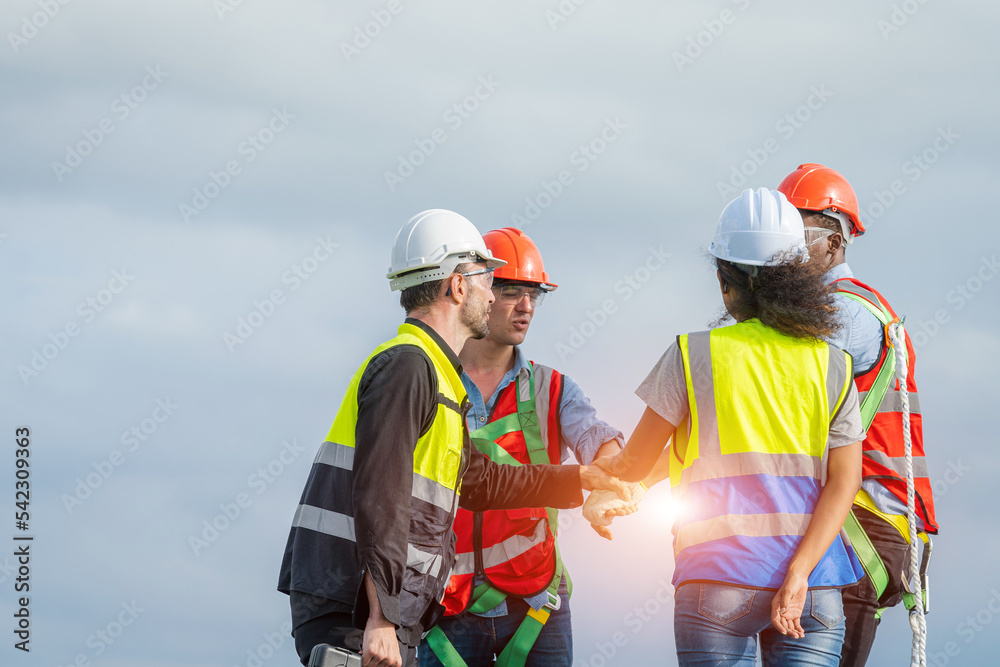 Construction workers in protective helmets are shaking hands while working on Solar cell on roof factory. Construction workers in protective helmets are shaking hands while working on Solar cell on roof factory.
