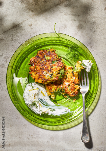 zucchini fritters on green glass plate with yogurt