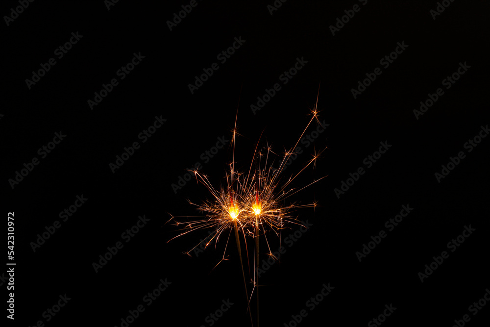 Two burning sparkler sticks glowing in dark
