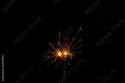 Two burning sparkler sticks glowing in dark