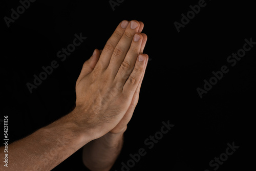 Man praying against black background, closeup view © New Africa