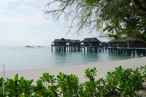 Beautiful wooden stilt houses along Pangkor laut with clean bean and lush greenery.
