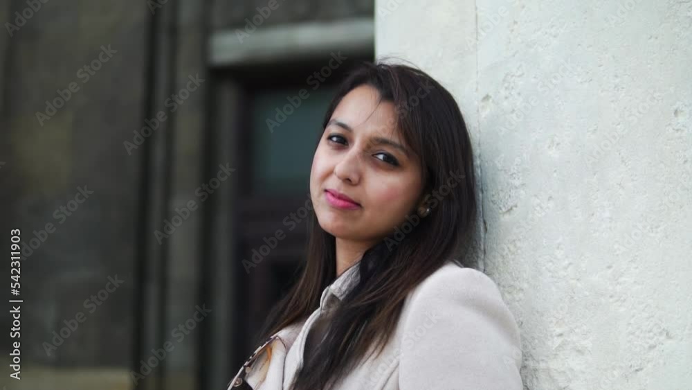 Portrait Of A South Asian Indian Woman Standing And Leaning Against Concrete Pillar Looking Directly To The Camera With Expressive Eyes. Warsaw, Poland - Medium Closeup Shot Portrait Of A South Asian Indian Woman Standing And Leaning Against Concrete Pillar Looking Directly To The Camera With Expressive Eyes. Warsaw, Poland - Medium Closeup Shot