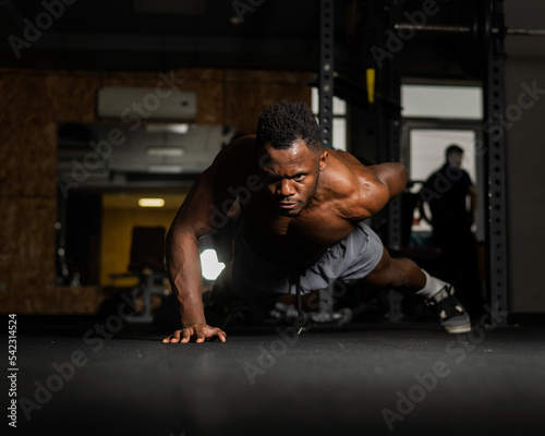 African american man doing one arm push ups in the gym. 