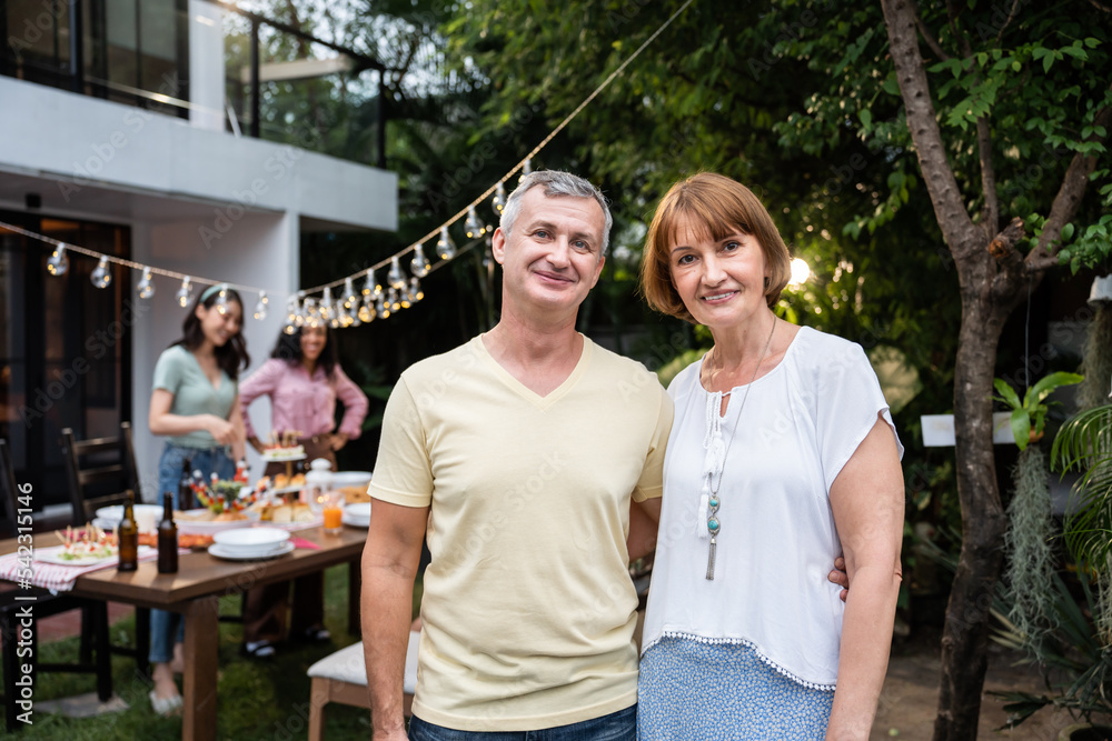 Portrait of senior couple looking at camera while having party outdoor. 