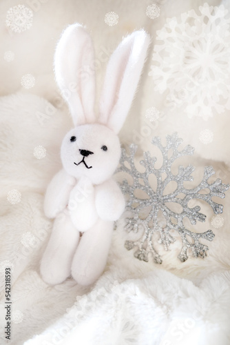 New Year decorations toys.Soft light. Christmas card with funny toy bunny on white fluffy background. Happy new year