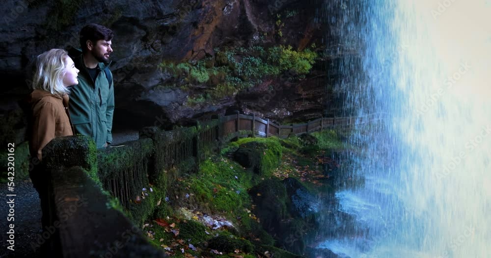 tourists enjoy the view from behind the Dry Falls waterfall, tourist attraction in Nantahala National Forest, North Carolina. A trail behind the natural waterfall in Appalachian mountains