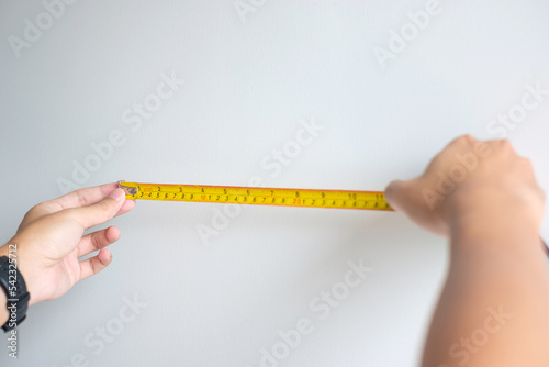 Man hand using tape measure for measuring with wall backgrounds at home. DIY, Interior design, repairing and improvement home or apartment concepts