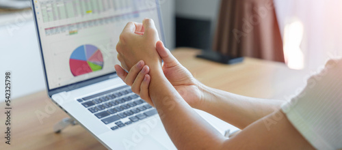 Woman having wrist pain when using laptop computer and mouse during working long time on workplace. De Quervain s tenosynovitis, rheumatism ergonomic, Carpal Tunnel Syndrome or Office syndrome concept photo