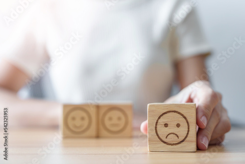 Hand choosing unhappy angry face from Emotion block. customer review, bad experience, negative feedback, satisfaction, survey, rating service, assessment, mood, world mental health day concept