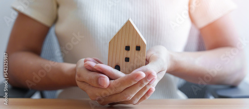 hand holding wood Home model. Real estate, buy and sale, Property insurance, rental, contract agreement, Happy Families, Homeless, Foster and family day concepts
