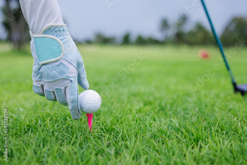 sport woman golf hand placing pink tee and ball into ground.