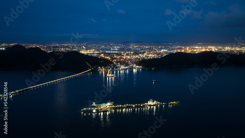 oil tanker ship loading in port, Oil tanker ship under cargo operations on typical shore station with clearly visible mechanical loading arms and pipeline at night refinery zone background,